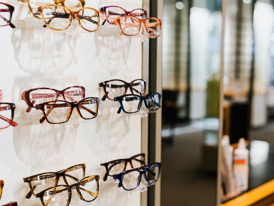 Assorted eyeglasses displayed on a shelf in an optician's store